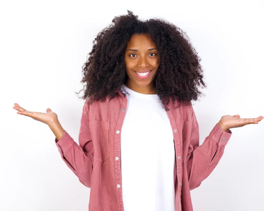 Une jeune femme sourit, les mains ouvertes, prête à poser ses questions